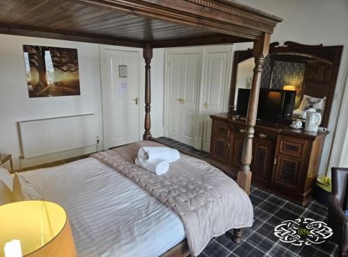a bedroom with a canopy bed and a television at Royal Marine Hotel Dunoon in Kirn