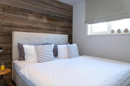 a bedroom with a white bed with a wooden wall at Sylter Meerholz in Tinnum