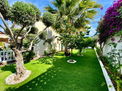 um jardim com palmeiras e relva verde em Karma Villa with views by HLCLUB Agency em Sant Pere de Ribes
