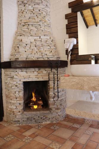 a stone fireplace in a bathroom with a sink and a tub at Pousada Cantinho das Estrelas in Monte Verde