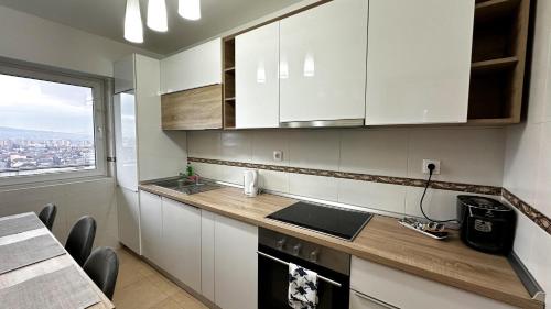 a kitchen with white cabinets and a counter with a window at AD Apartments in Cluj-Napoca