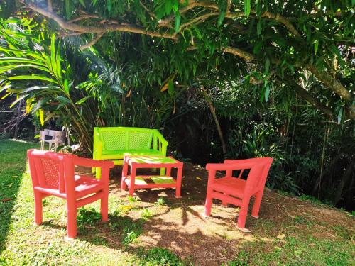 three colorful chairs and a table in the grass at La Villa Mil'Or, Idéale pour vos petits évènements & Magnifique vue sur la Baie du Robert in Le Robert