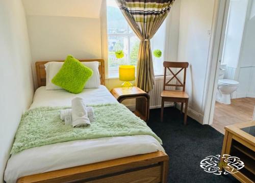 a bedroom with a bed with green pillows and a window at Royal Marine Hotel Dunoon in Kirn