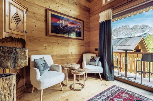 a room with two chairs and a table and a large window at Hotel Villa Alpina ***S in Cortina dʼAmpezzo