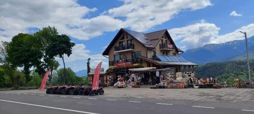 a store on the side of a road with a building at Popasul de Wis in Moieciu de Jos