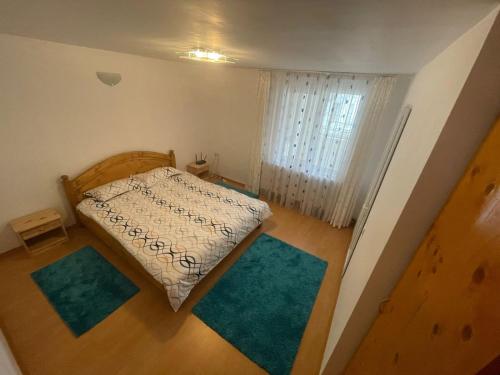 a small bedroom with a bed and two blue rugs at La Moieciu pe Deal in Moieciu de Jos