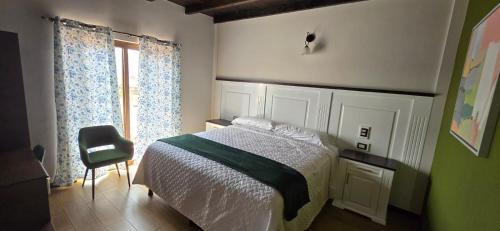 a bedroom with a bed and a chair and a window at Apartamento 3 Premiere de Occidente in Quetzaltenango