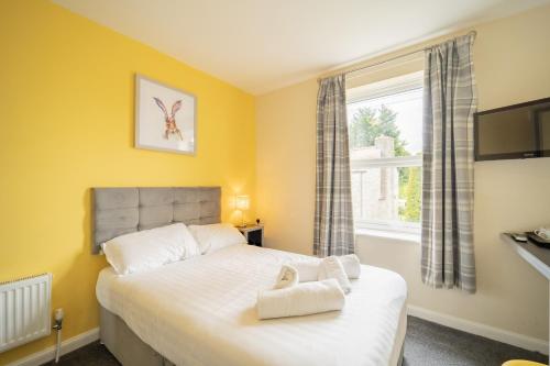 sypialnia z łóżkiem z żółtymi ścianami i oknem w obiekcie The Well Inn w mieście Shepton Mallet