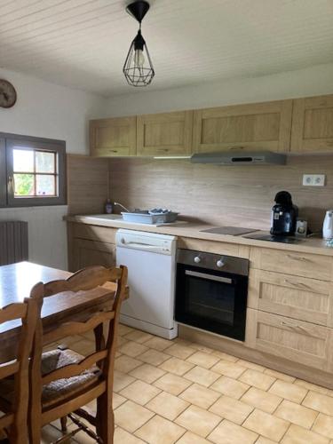 une cuisine avec une table, une cuisinière et un lave-vaisselle dans l'établissement Longère campagne 10 pers. proche Guédelon, à Sougères-en-Puisaye