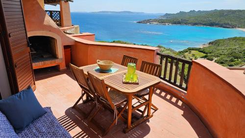 een tafel en stoelen op een balkon met uitzicht op de oceaan bij Le Residenze La Marmorata in Santa Teresa Gallura