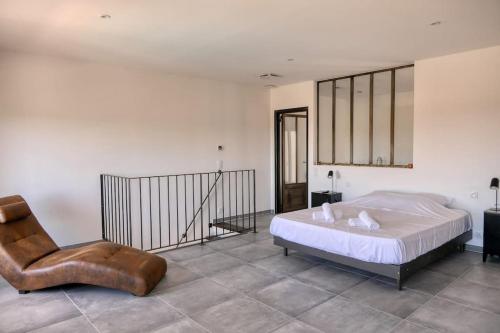 une chambre avec un lit et une chaise dans l'établissement Maison cœur village piscine wifi 2 pers, à Vacqueyras