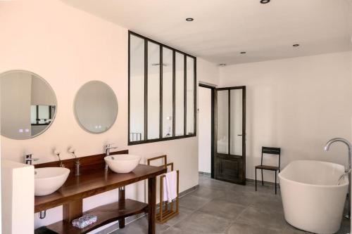 une salle de bain avec deux lavabos et deux miroirs dans l'établissement Maison cœur village piscine wifi 2 pers, à Vacqueyras