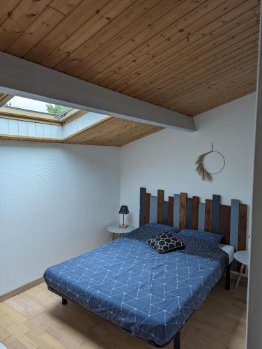 - une chambre avec un lit bleu et un plafond en bois dans l'établissement Appartement 4 personnes bord mer, à Yves