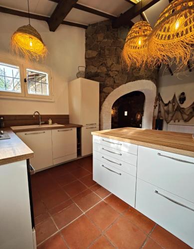 - une cuisine avec des placards blancs et un mur en pierre dans l'établissement Villa Familiale - Golfe de Saint Tropez, à Grimaud