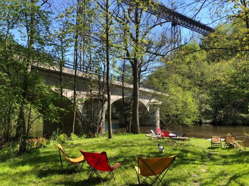 a group of chairs sitting in the grass next to a river at Chambre sur une ile in Saint-Bonnet-de-Rochefort