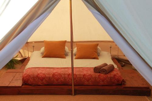 a bed in a tent with two pillows at Casa de campo glamping in Eželiškės