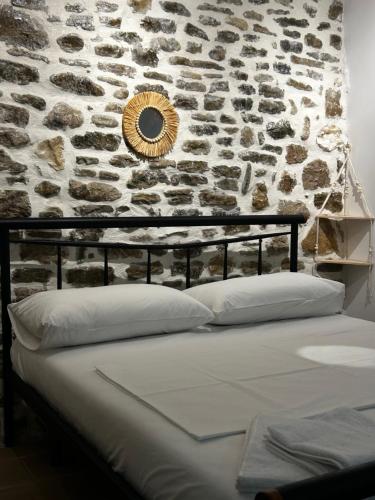 uma cama num quarto com uma parede de pedra em Vourtaréa Guesthouse em Himare