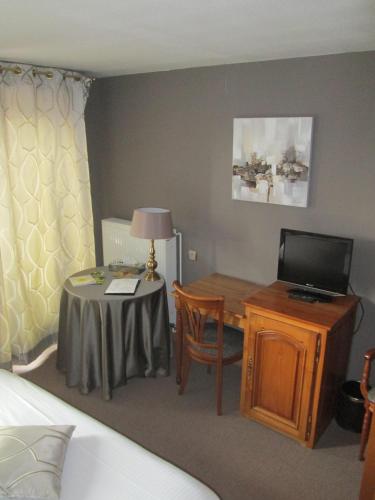 a bedroom with a desk and a table with a television at Logis Hotel Restaurant Au Boeuf Rouge in Niederschaeffolsheim