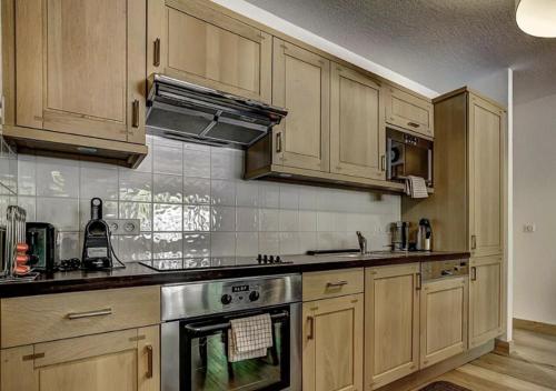 a kitchen with wooden cabinets and a stainless steel oven at Charming Apartment Chamonix Valley in Vallorcine