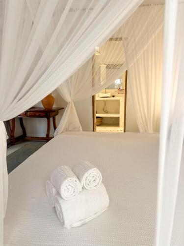 two towels on a white bed in a bedroom at Casa da Glória Trancoso - Pousada Boutique in Trancoso