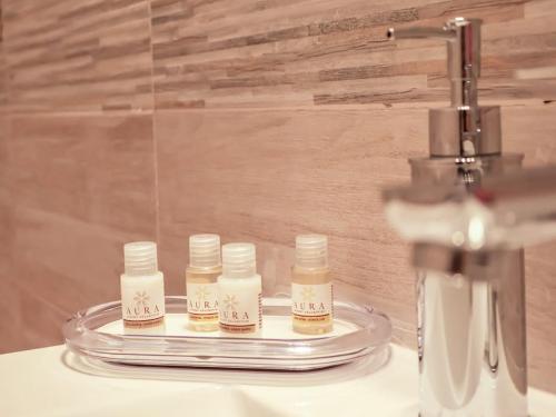 vier flessen vochtinbrengende crèmes op een aanrecht naast een gootsteen bij Casa Vacanze Michelangelo in Letojanni