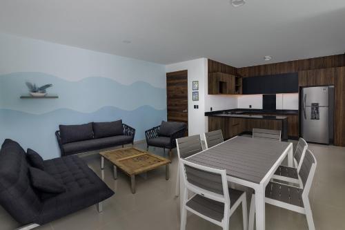 a kitchen and living room with a table and chairs at Angelina 28 Beachfront and Family Apartments - Modern and Relaxing Long Stays - 20 min from Cancun Airport in Puerto Morelos