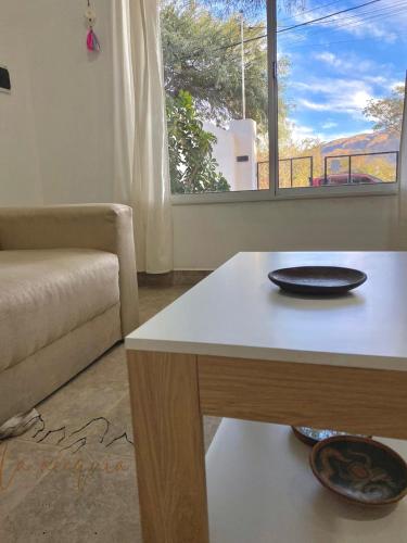 a living room with a table and a couch and a window at La acequia casa in Cafayate