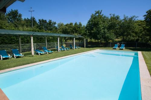 an empty swimming pool with blue chairs at Quinta do Caminho, AL in Valença