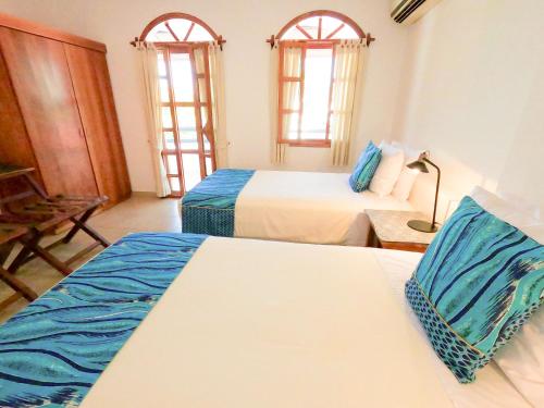a hotel room with two beds and two windows at Hotel Galapagos Suites B&B in Puerto Ayora