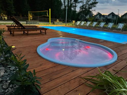 a hot tub sitting on a deck next to a swimming pool at Baltic Natur Park - Holiday Resort in Niechorze
