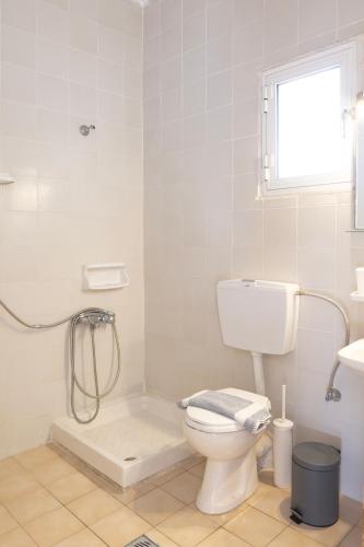 a white bathroom with a toilet and a shower at GEORGE AND MARIOS STUDIOS Inn in Ammouliani
