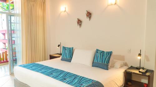 a bedroom with a bed with blue and white pillows at Hotel Galapagos Suites B&B in Puerto Ayora