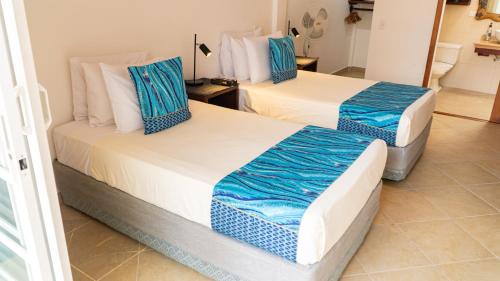 two beds in a room with blue and white at Hotel Galapagos Suites B&B in Puerto Ayora