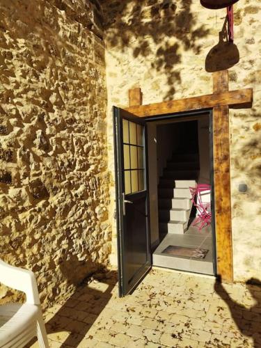 un bâtiment en pierre avec une porte ouverte et des escaliers dans l'établissement Beau logis indépendant dans mas piscine 2 pers, à Pujaut