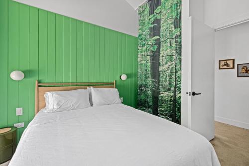 a bedroom with a green wall and a bed at Owlwood in Harbert
