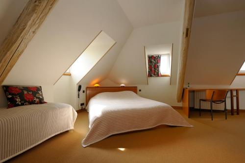 - une chambre mansardée avec un lit et un bureau dans l'établissement La Bonneterie, à Andlau