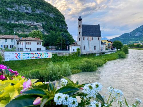 una iglesia junto a un río con flores en Casa Ambra, en Trento