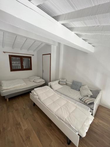 deux lits dans une chambre aux murs blancs et au parquet dans l'établissement Maison climatisatée 2 chambres extérieur barbecue parking gratuit 600m mer, à Saint Cyprien Plage