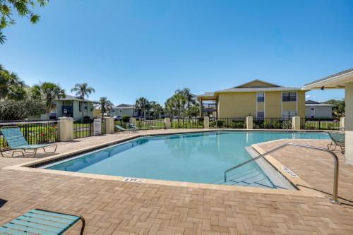 a swimming pool with two chairs and a house at Walk to Pier St Augustine Beach Condo with Balcony! in Saint Augustine Beach