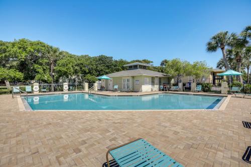 a swimming pool with two chairs and a house at Walk to Pier St Augustine Beach Condo with Balcony! in Saint Augustine Beach