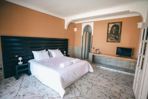 a bedroom with a large white bed and a television at Hôtel Calipau Riad Maison d'Hôtes in Dakhla
