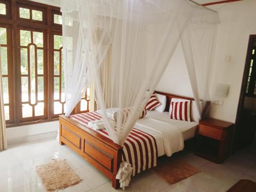 a bedroom with a canopy bed with red and white pillows at Maple Home Stay in Ella