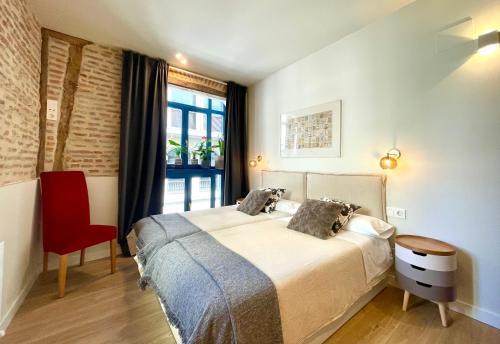 a bedroom with a bed and a red chair at Lauramer Plaza Nueva in Bilbao