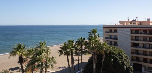 a hotel on the beach with palm trees and the ocean at Hotel Mediterráneo by Croma in Estepona