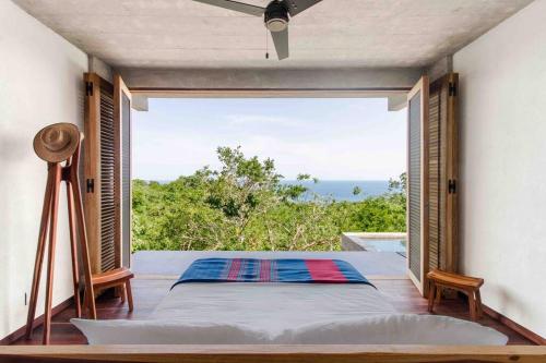 a bedroom with a bed and a large window at Casa La Distancia Mazunte Sustainable House in Mazunte