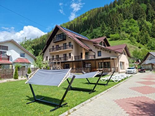 a resort with two hammocks in front of a building at Pensiunea El Monte SPA in Rucăr