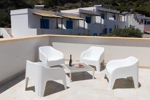 a patio with white chairs and a table and a bottle of wine at Marettimo Vacanze in Marettimo