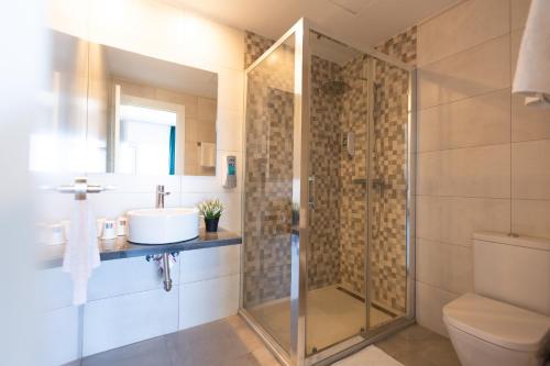 uma casa de banho com uma cabina de duche em vidro e um lavatório. em Hotel Mediterráneo em Estepona