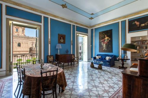 uma sala de estar com paredes azuis e uma mesa e cadeiras em Cathedral View Apartments em Palermo