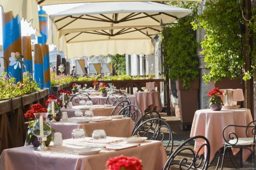 ヴェネツィアにあるカ サグレド ホテルのテーブルと椅子、傘が備わるレストラン